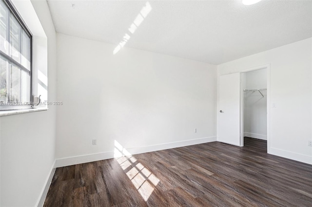 unfurnished bedroom with a textured ceiling, a closet, and dark wood-type flooring