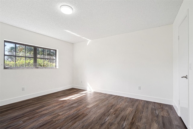 empty room with dark wood-type flooring and a textured ceiling