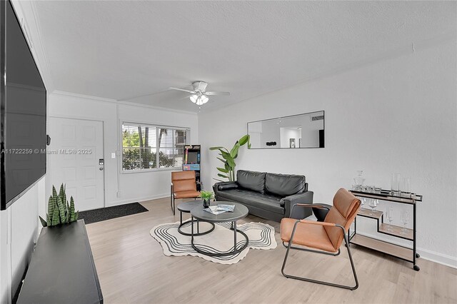 living room featuring ceiling fan with notable chandelier, crown molding, and light hardwood / wood-style flooring