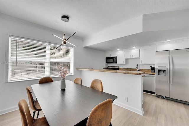 dining room featuring ornamental molding, sink, a textured ceiling, and light hardwood / wood-style flooring