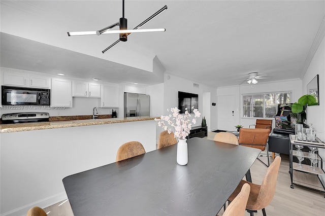 dining space with ceiling fan, ornamental molding, sink, and light hardwood / wood-style flooring