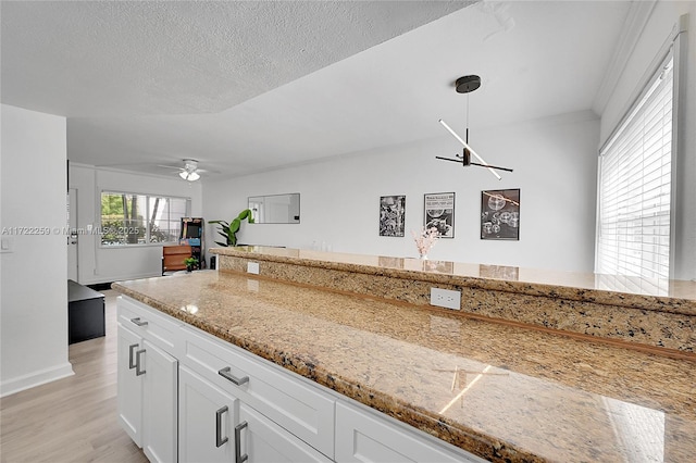 kitchen with white cabinetry, hanging light fixtures, ceiling fan, light hardwood / wood-style floors, and a textured ceiling