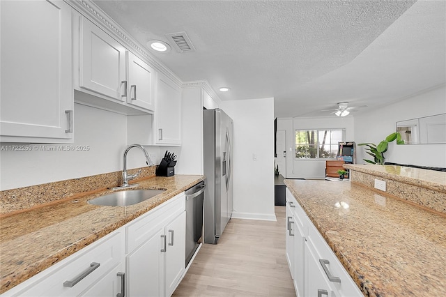 kitchen featuring sink, stainless steel appliances, light stone countertops, a textured ceiling, and white cabinets