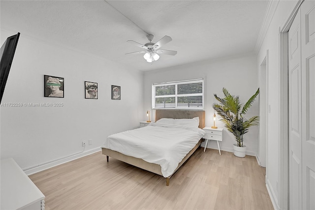 bedroom featuring ceiling fan, ornamental molding, light hardwood / wood-style floors, and a textured ceiling