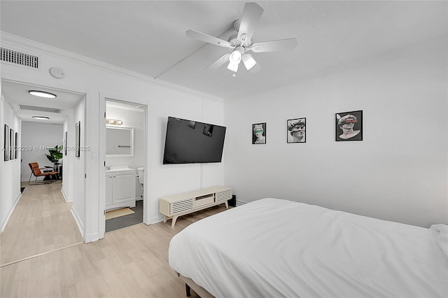 bedroom featuring ceiling fan, connected bathroom, ornamental molding, light hardwood / wood-style floors, and a textured ceiling