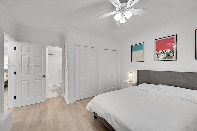 bedroom featuring crown molding, ensuite bath, light hardwood / wood-style flooring, multiple closets, and ceiling fan