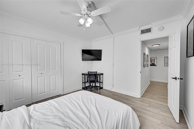 bedroom featuring crown molding, ceiling fan, light wood-type flooring, and a closet