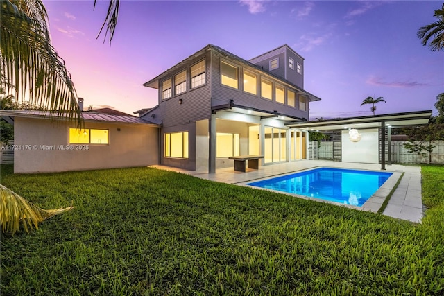 back house at dusk with a fenced in pool, a yard, and a patio