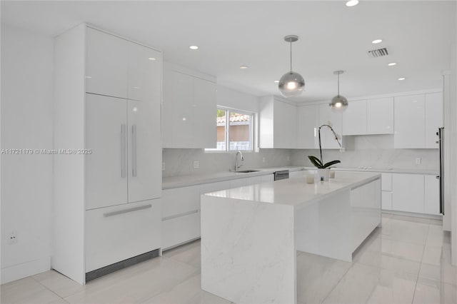 kitchen featuring white cabinets, sink, hanging light fixtures, decorative backsplash, and a kitchen island