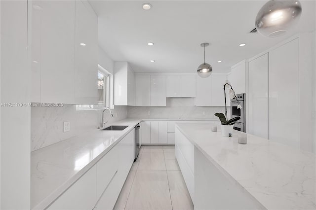 kitchen with light stone counters, stainless steel dishwasher, sink, pendant lighting, and white cabinets