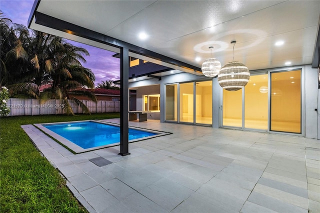 pool at dusk with a notable chandelier