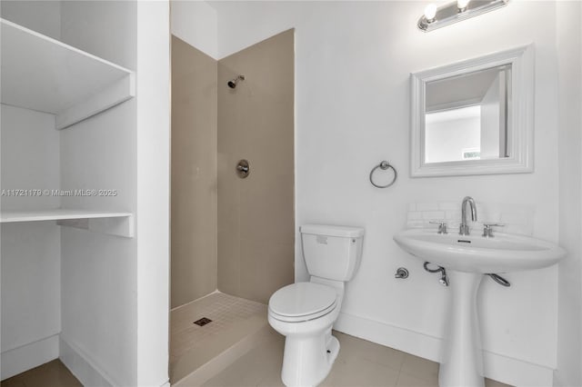 bathroom featuring tile patterned flooring, sink, toilet, and tiled shower