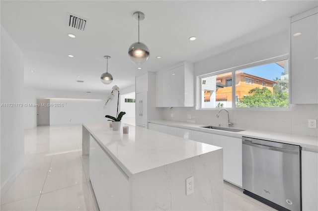 kitchen featuring white cabinetry, stainless steel dishwasher, and decorative light fixtures