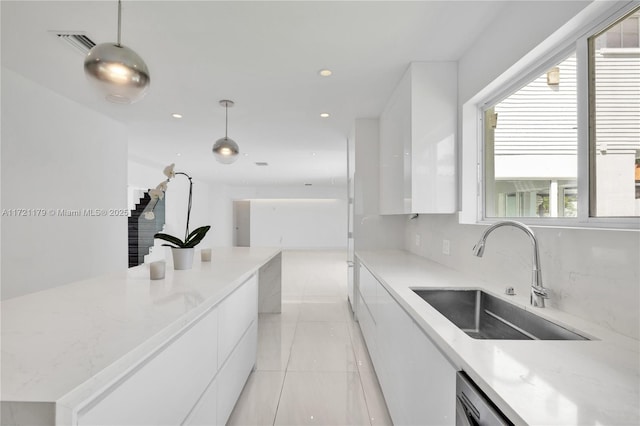 kitchen with light stone countertops, sink, pendant lighting, decorative backsplash, and white cabinets