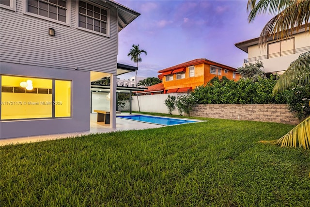 yard at dusk with a patio and a fenced in pool