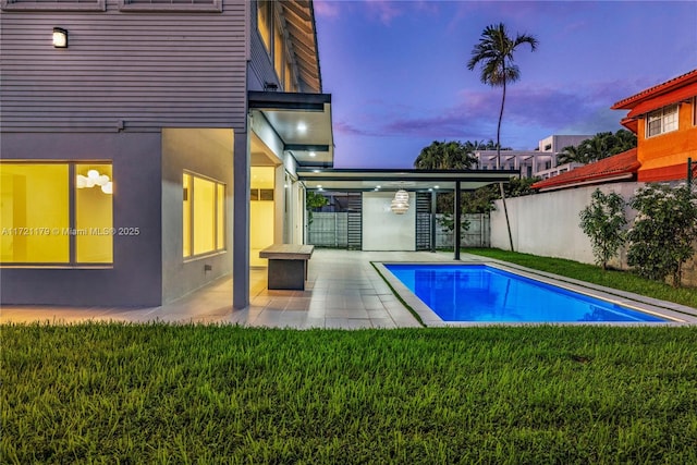 pool at dusk with a lawn and a patio