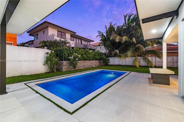 pool at dusk featuring a patio