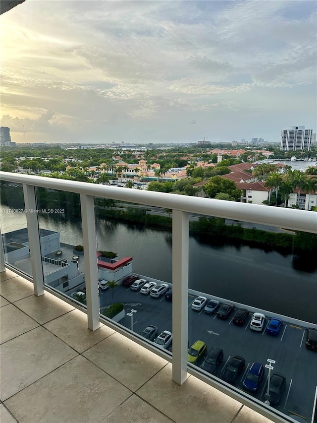 balcony at dusk featuring a water view