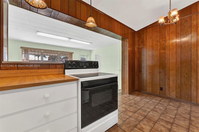 kitchen with electric range, decorative light fixtures, wooden walls, and a notable chandelier