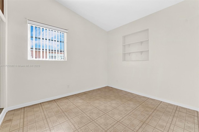 spare room featuring built in shelves and lofted ceiling