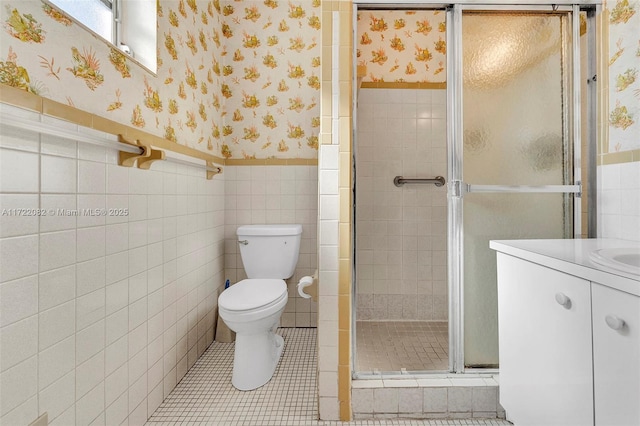 bathroom featuring vanity, tile patterned flooring, toilet, walk in shower, and tile walls