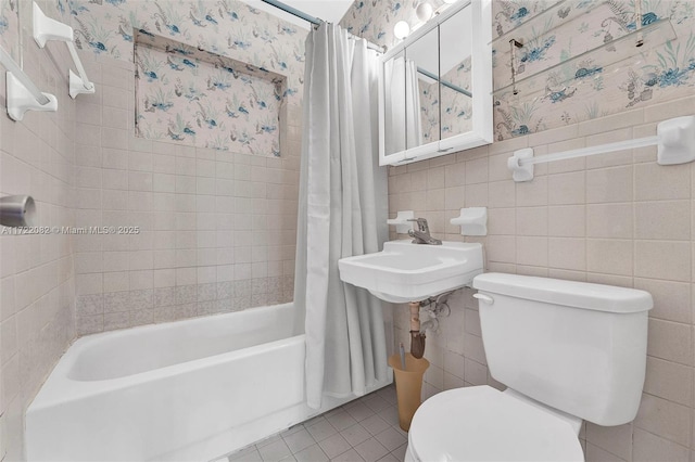 full bathroom featuring sink, shower / bath combo, tile patterned floors, toilet, and tile walls