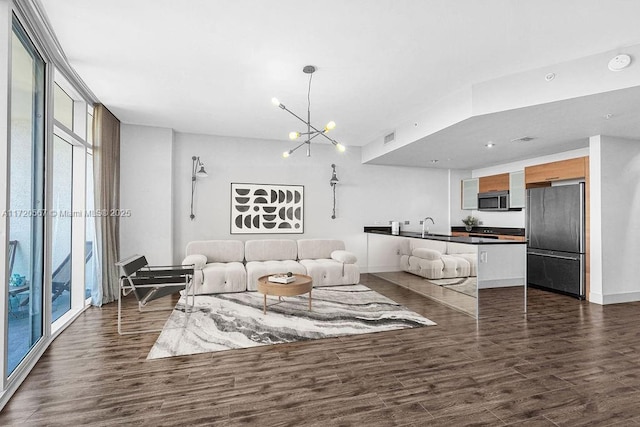 living room featuring sink, dark wood-type flooring, a wall of windows, and a notable chandelier