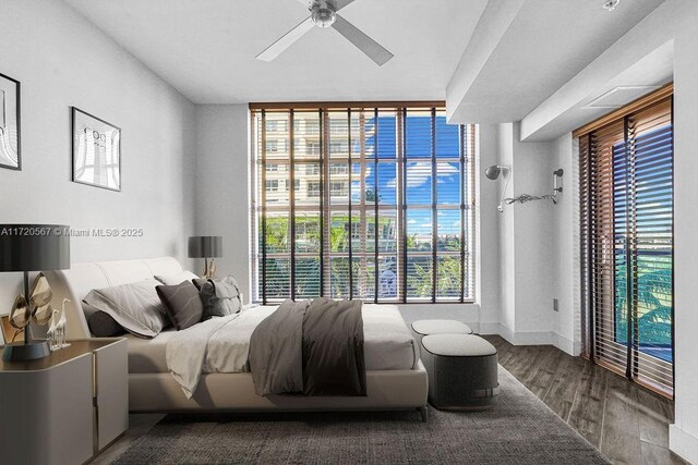 bedroom featuring a wall of windows, hardwood / wood-style flooring, ceiling fan, and a water view