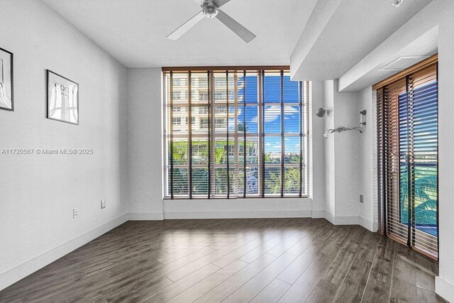 spare room featuring plenty of natural light, ceiling fan, and dark wood-type flooring