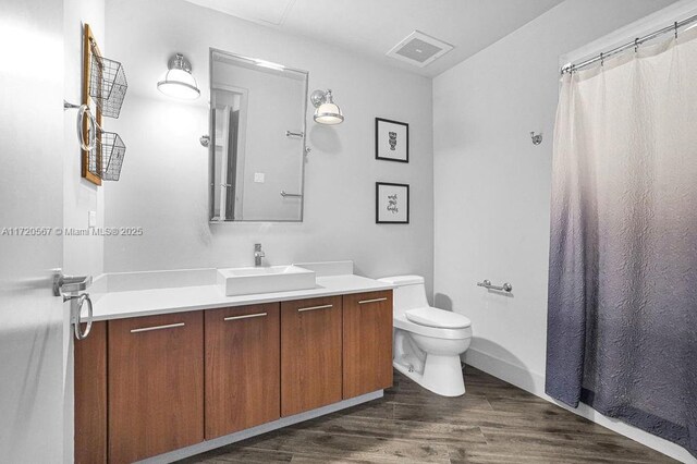 bathroom with a shower with curtain, vanity, wood-type flooring, and toilet