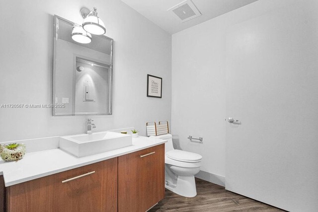 bathroom with hardwood / wood-style flooring, vanity, and toilet