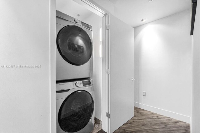 laundry area with dark wood-type flooring and stacked washer and clothes dryer