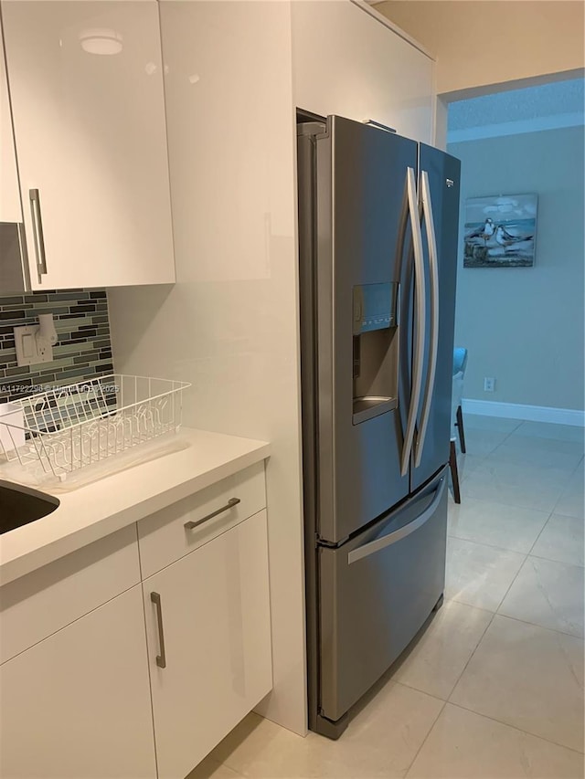 kitchen with backsplash, white cabinetry, stainless steel fridge, and light tile patterned flooring