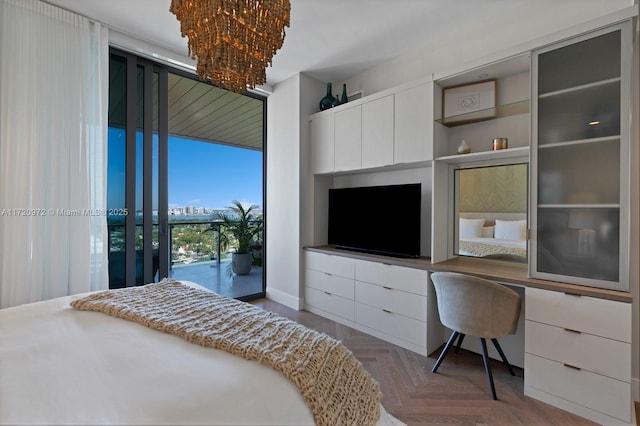 bedroom featuring access to exterior, dark parquet flooring, built in desk, and floor to ceiling windows