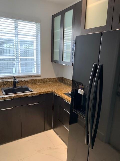 kitchen featuring dark brown cabinetry, sink, and black refrigerator with ice dispenser