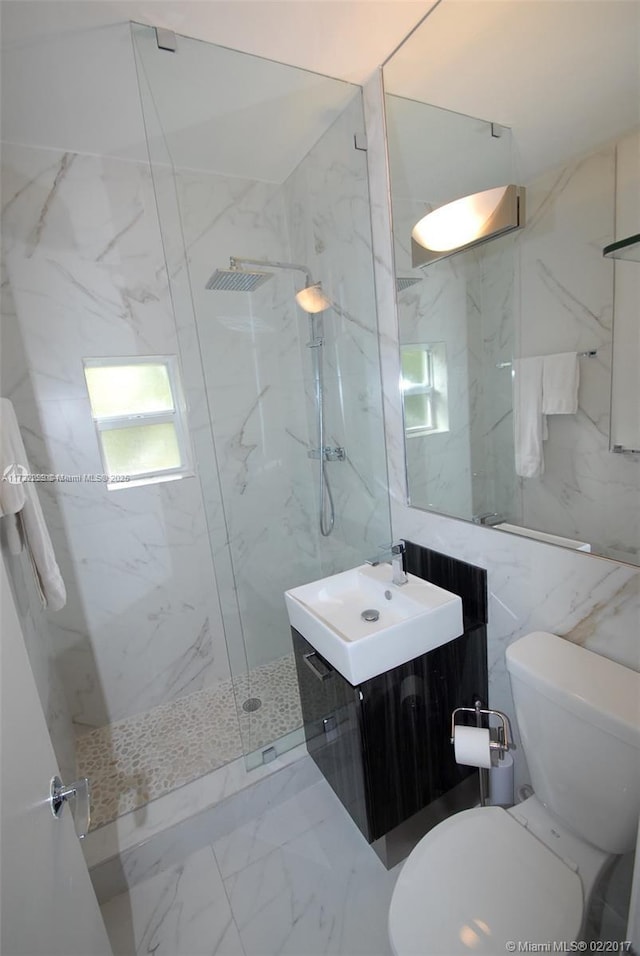 bathroom featuring a tile shower, vanity, toilet, and tile walls