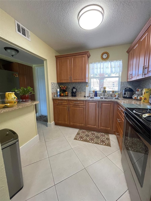 kitchen featuring a textured ceiling, tasteful backsplash, stainless steel electric range oven, and sink