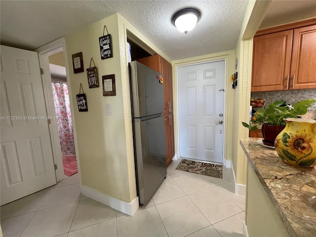 interior space with a textured ceiling and light tile patterned flooring