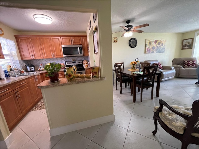 kitchen featuring light tile patterned flooring, a textured ceiling, appliances with stainless steel finishes, and tasteful backsplash