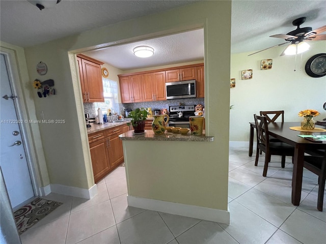 kitchen with decorative backsplash, ceiling fan, light tile patterned floors, and appliances with stainless steel finishes