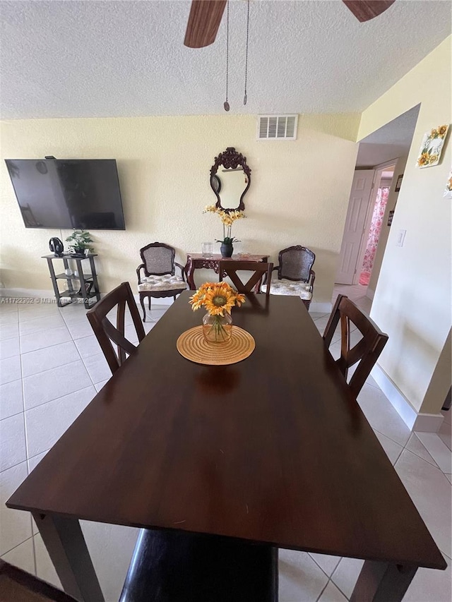 tiled dining space with a textured ceiling and ceiling fan