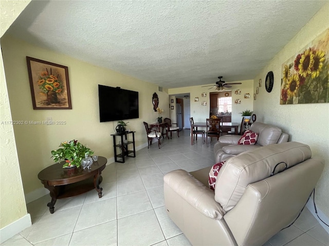 tiled living room with ceiling fan and a textured ceiling