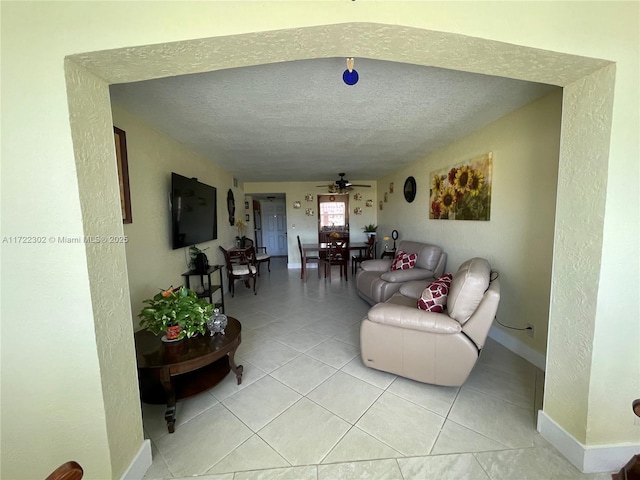 tiled living room with ceiling fan and a textured ceiling