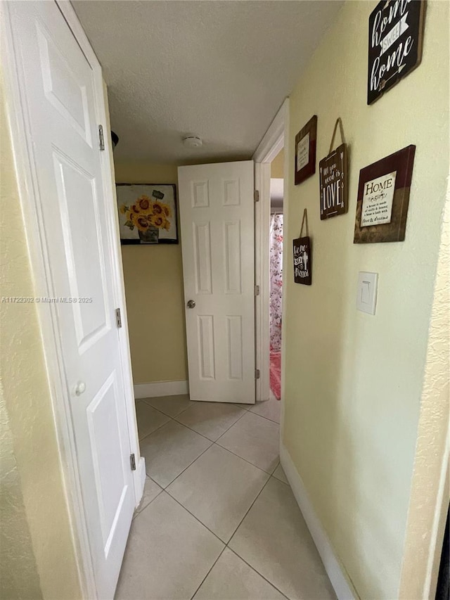 hall featuring light tile patterned floors and a textured ceiling