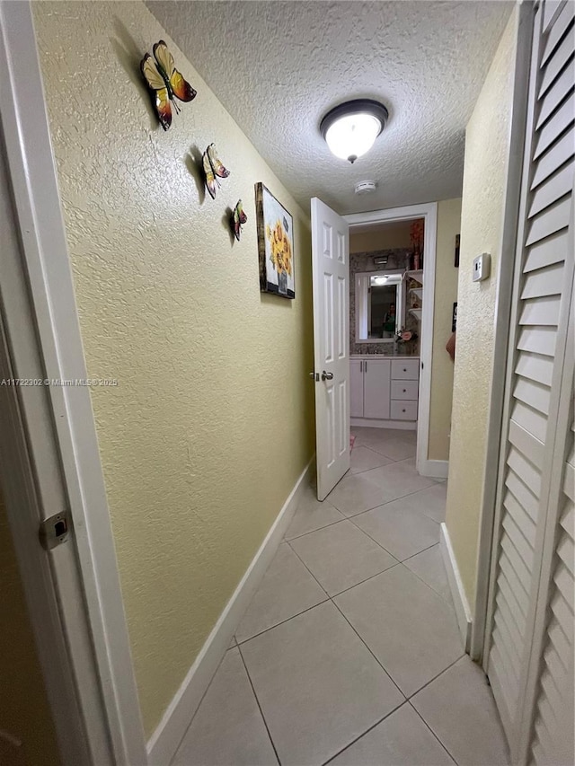 hall with light tile patterned floors and a textured ceiling