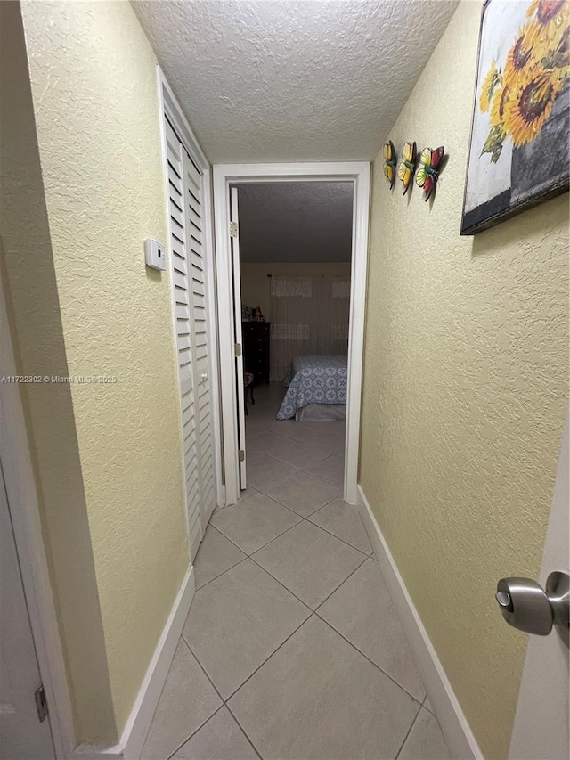 hallway with light tile patterned flooring and a textured ceiling