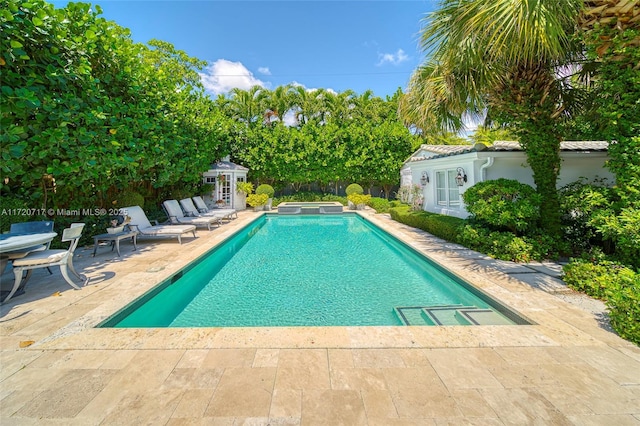 view of swimming pool featuring an in ground hot tub, a patio, and an outdoor structure