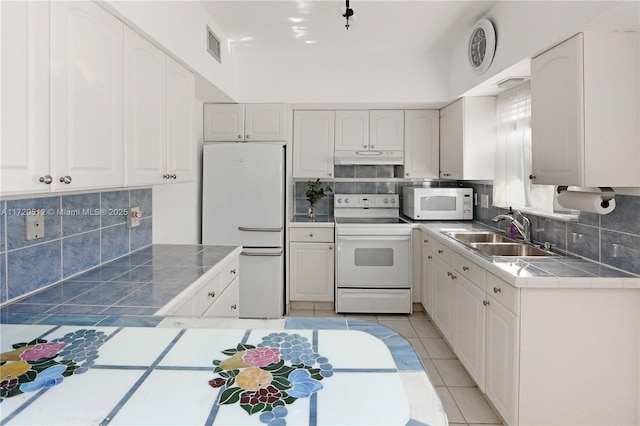 kitchen with tile countertops, white cabinets, white appliances, and sink