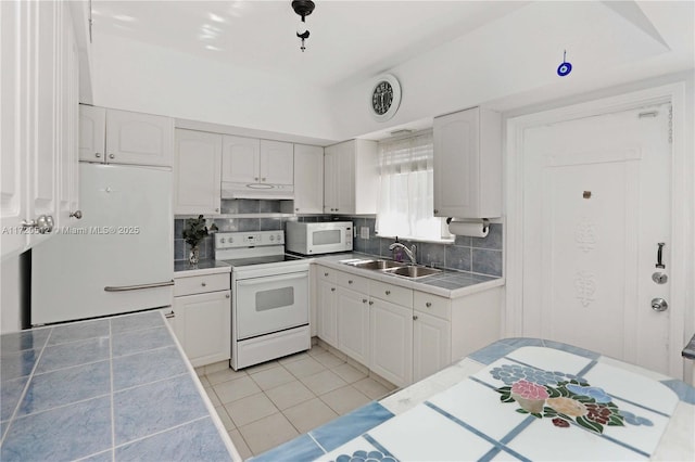 kitchen with tile countertops, white cabinetry, white appliances, and sink