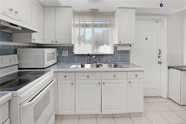 kitchen featuring white cabinetry, sink, light tile patterned floors, and white appliances